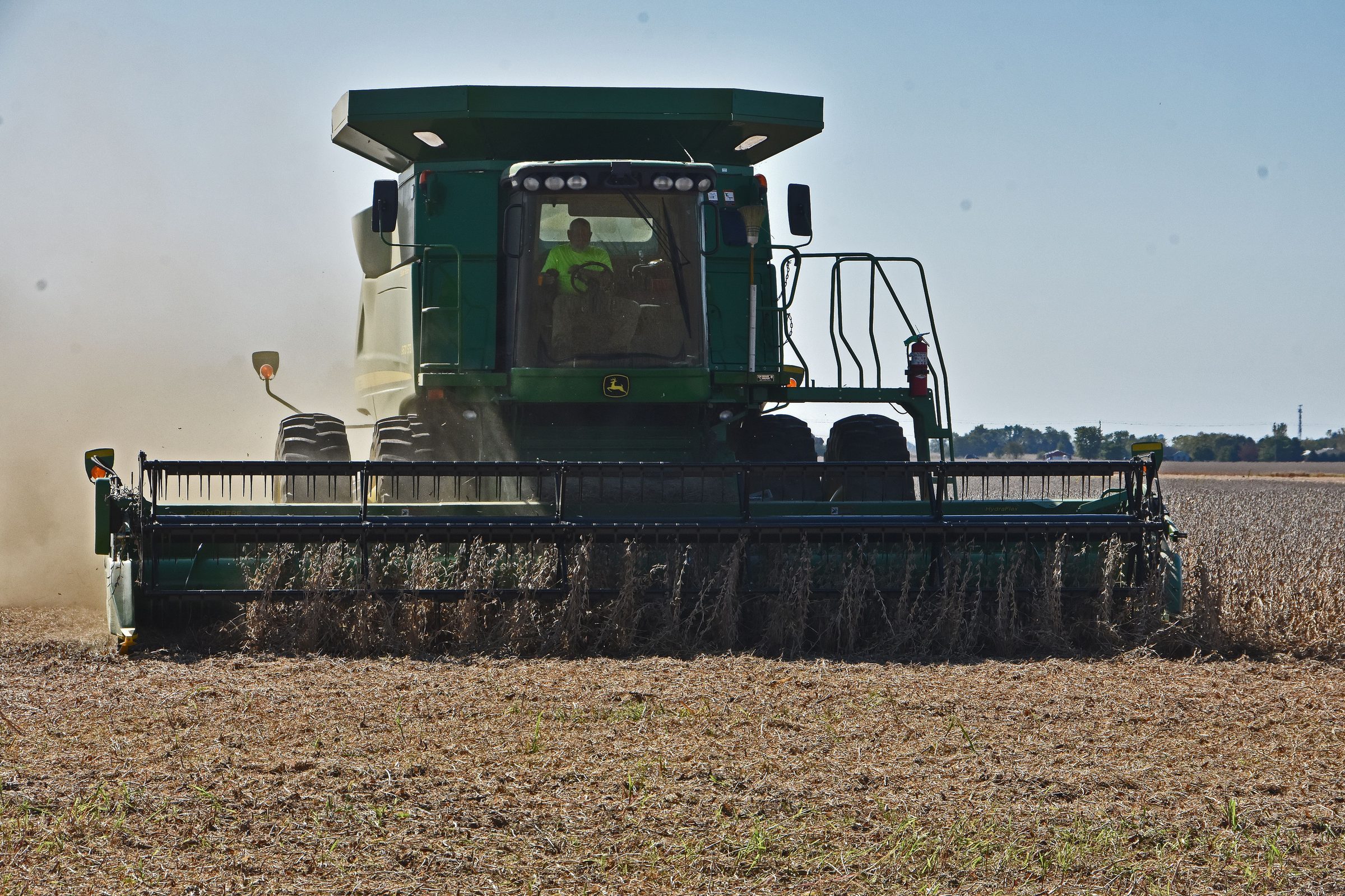 Tractor pulling a seed drill through a field at golden hour